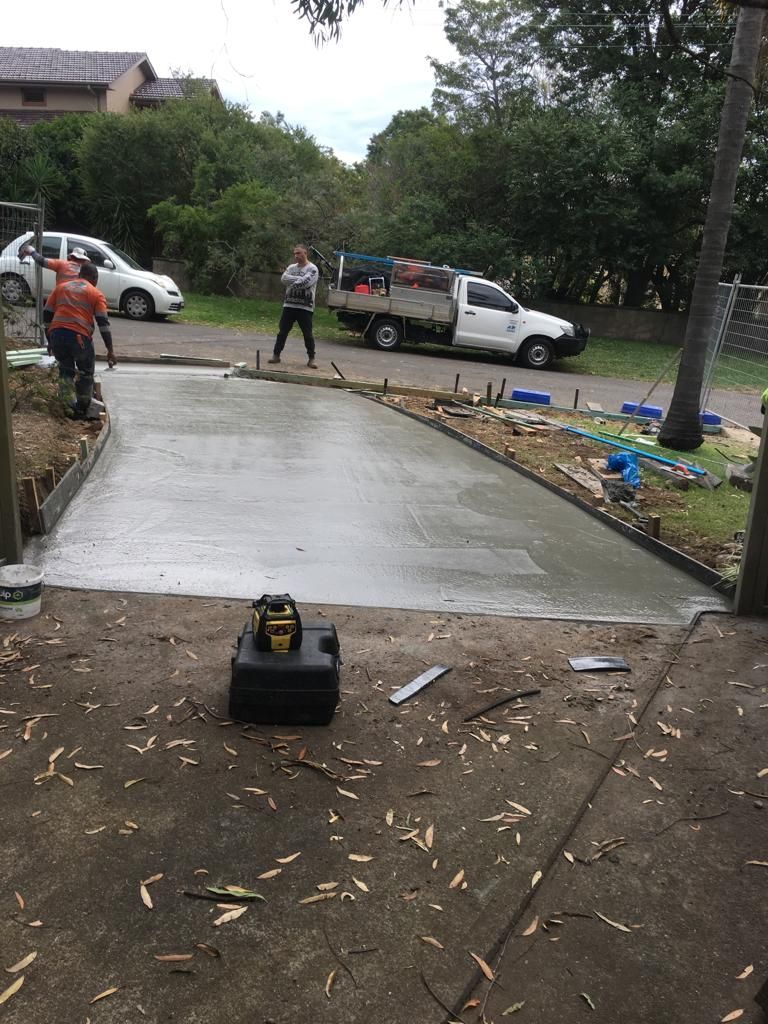 A group of people are working on a concrete driveway.