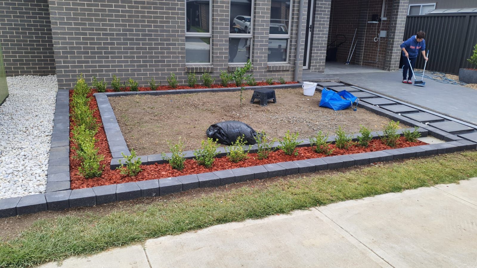 A man is standing in front of a brick house.