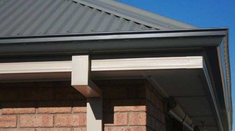 A close up of a gutter on the side of a house.
