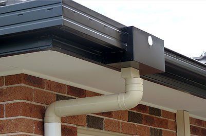 A close up of a gutter on the side of a brick building.