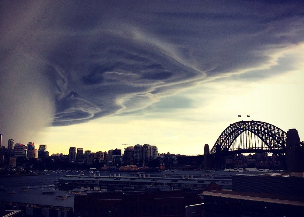 A cloudy sky over a city with a bridge in the distance