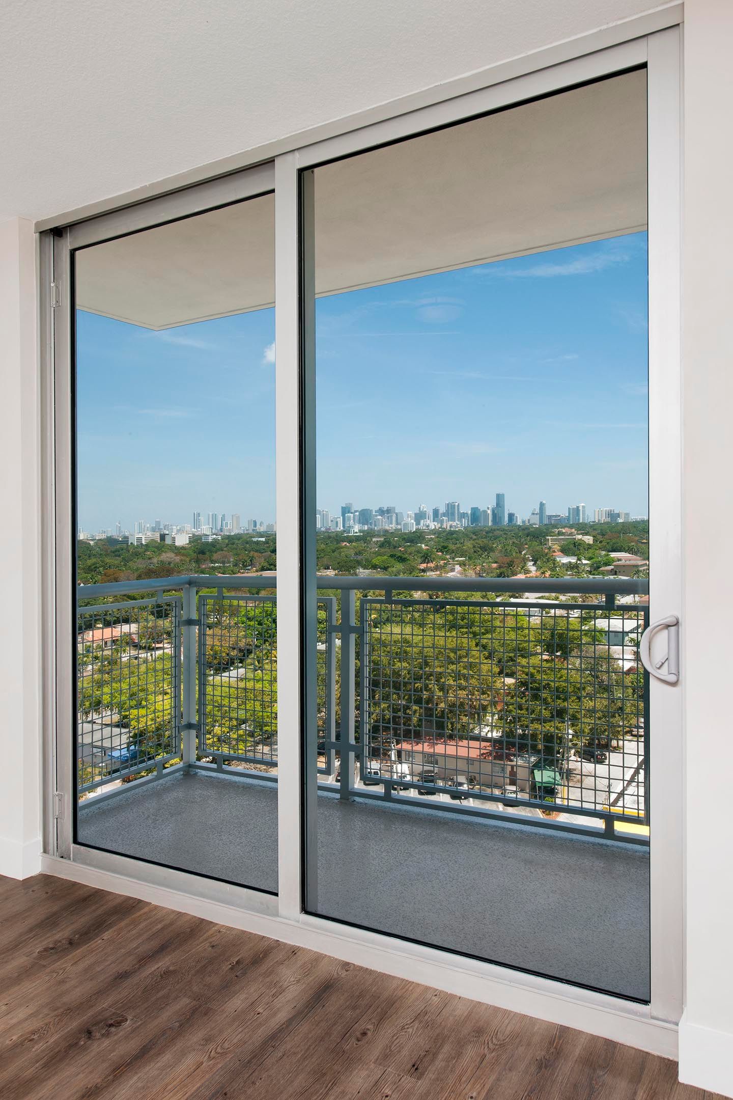 Sliding glass door to balcony with city skyline view.