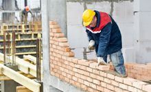 a builder laying bricks to create a wall
