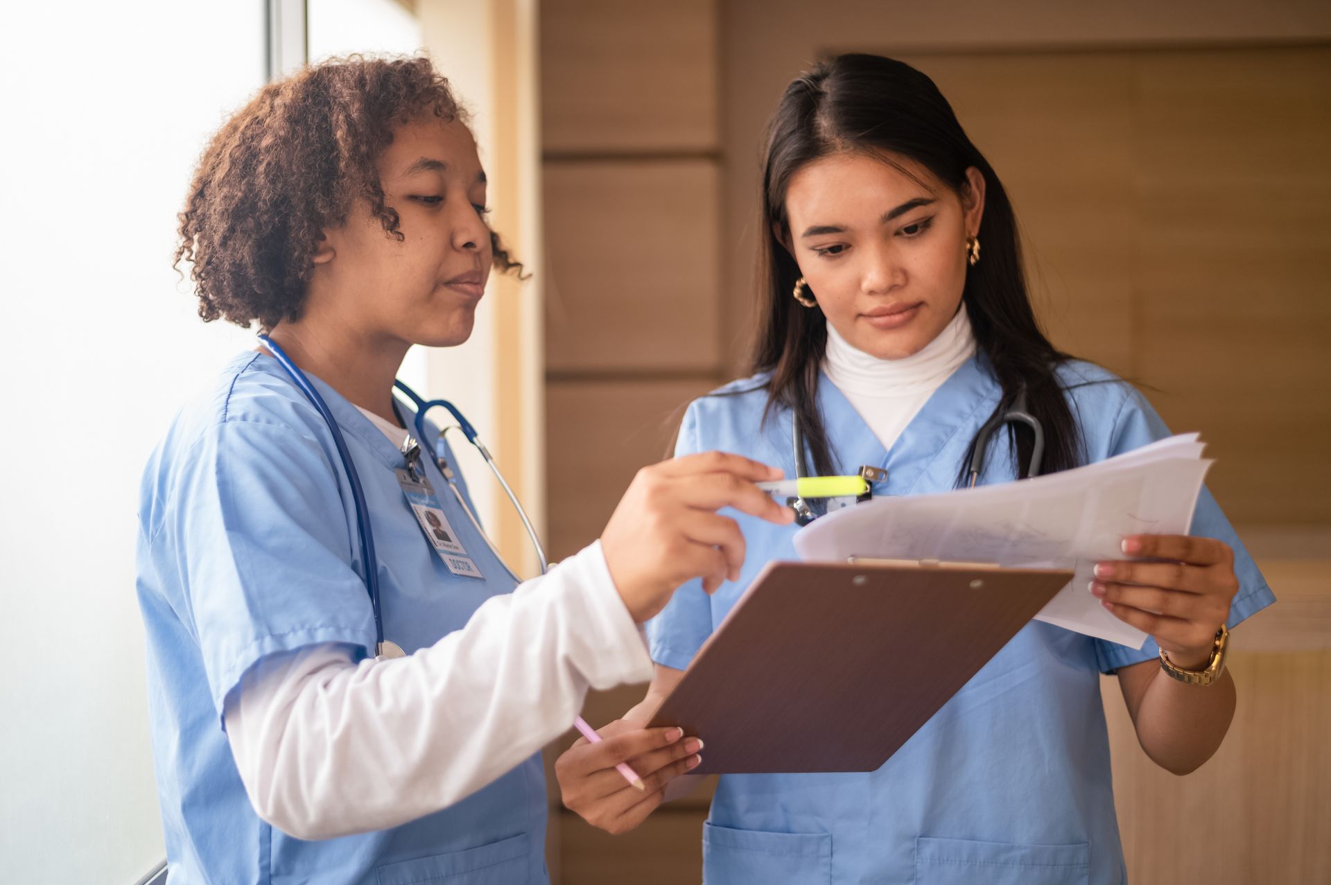 Two nurses are looking at a clipboard together.