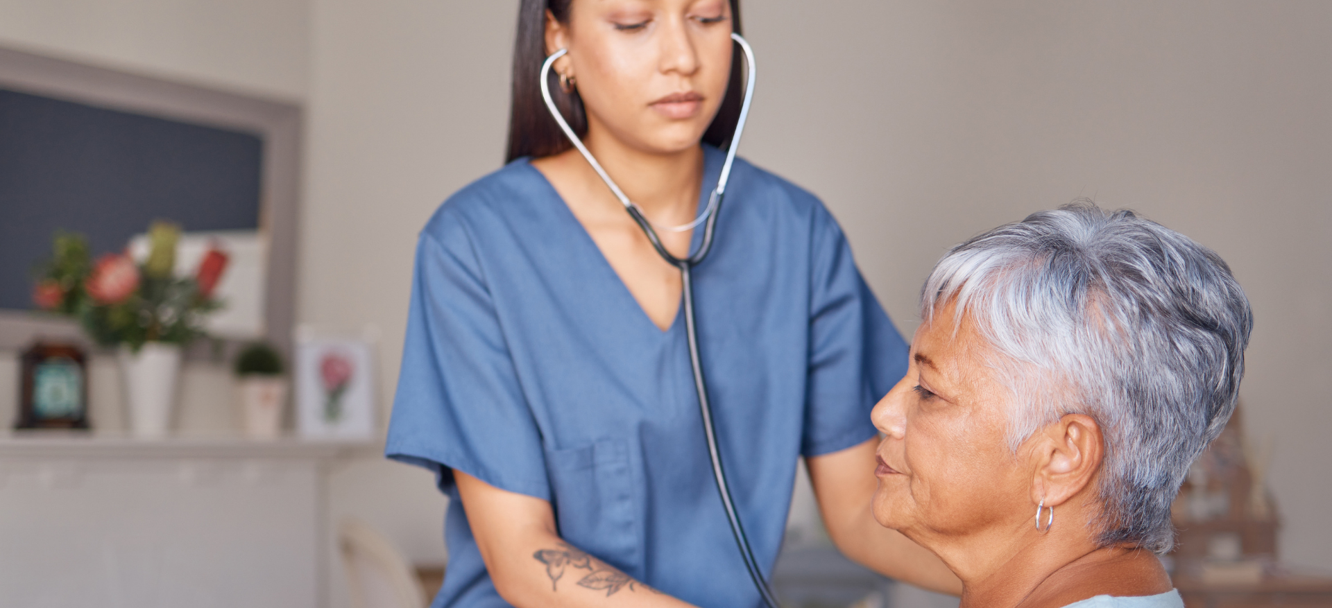 A nurse is listening to an older woman 's heartbeat with a stethoscope.