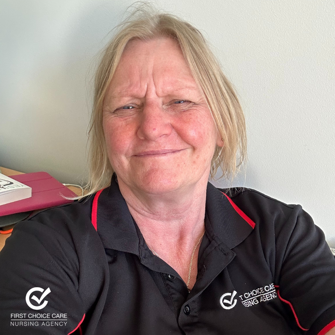 A woman wearing a black and red polo shirt is smiling for the camera.