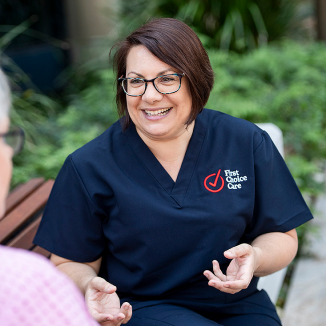 A woman wearing glasses and a blue shirt that says first choice care