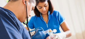 A doctor and nurse are working on a patient in a hospital room.