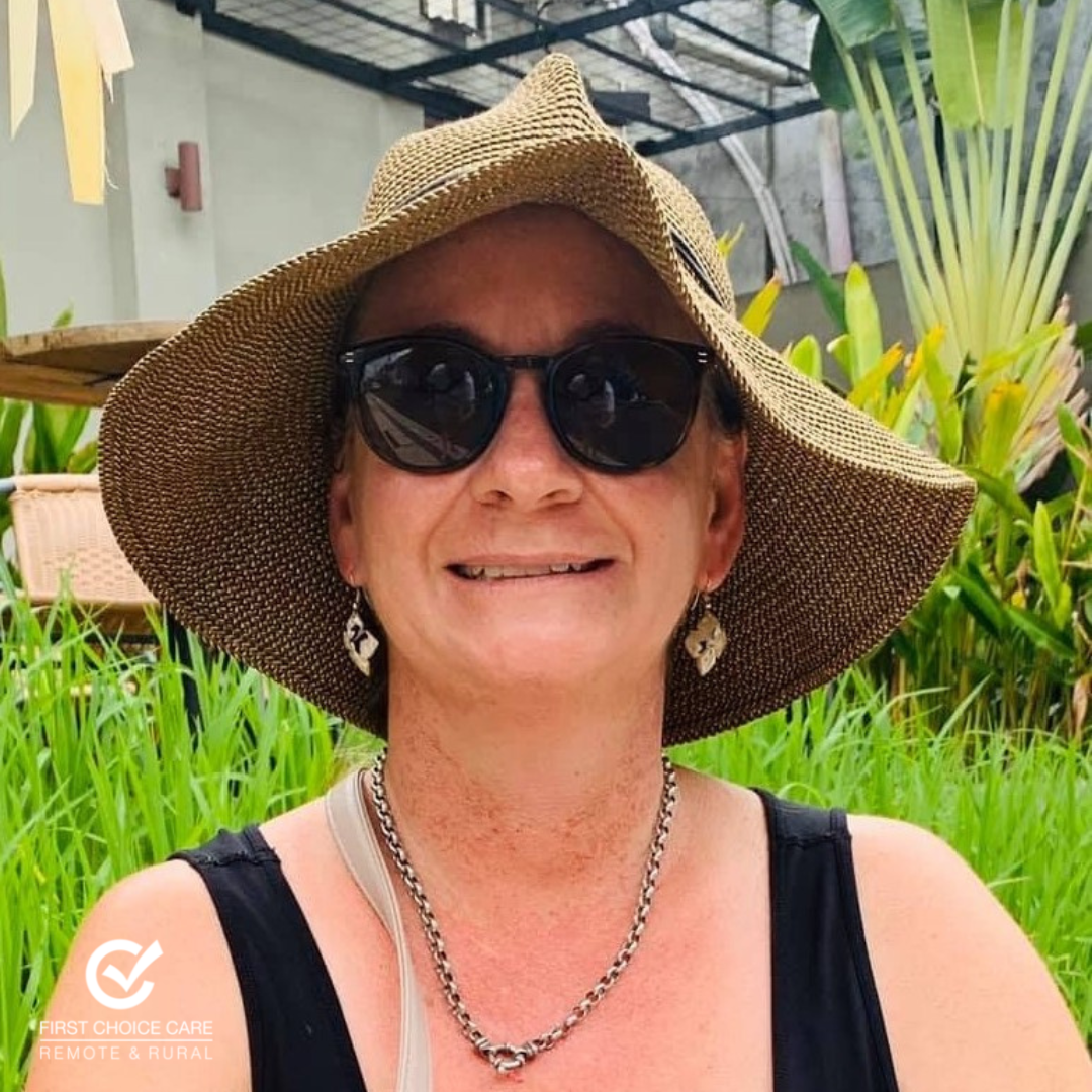 A woman wearing a hat and sunglasses is smiling for the camera