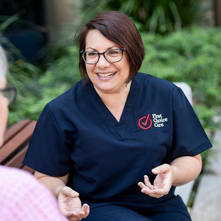 A nurse is sitting on a bench talking to a patient.