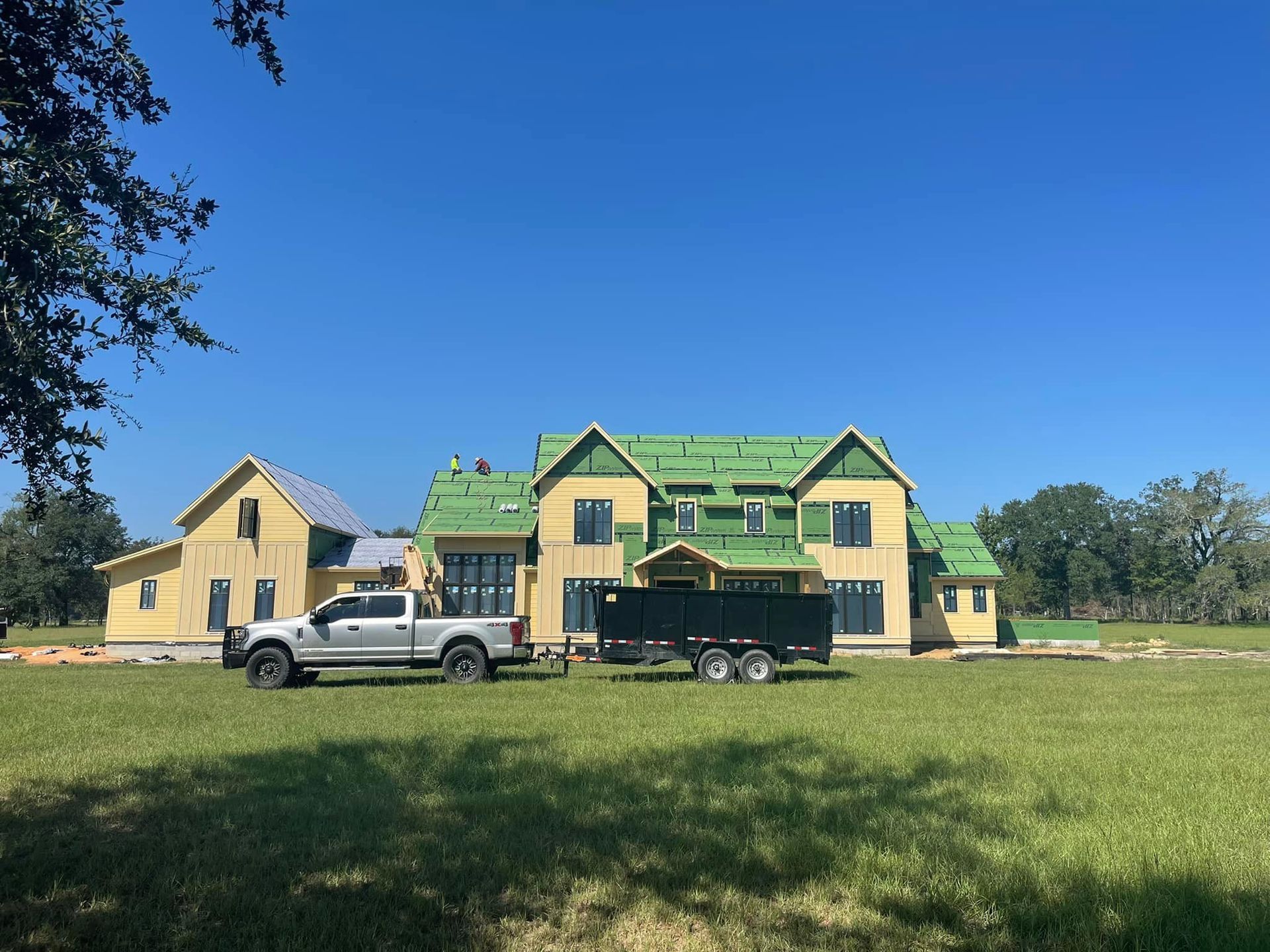 A white truck is parked in front of a large house under construction.