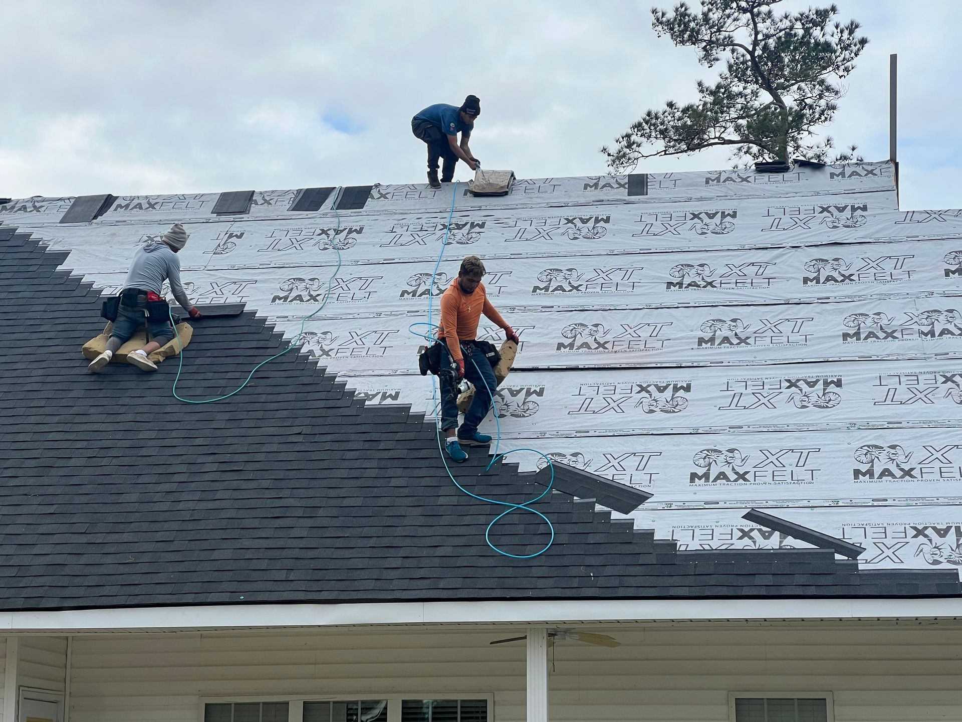 A group of men are working on the roof of a house.