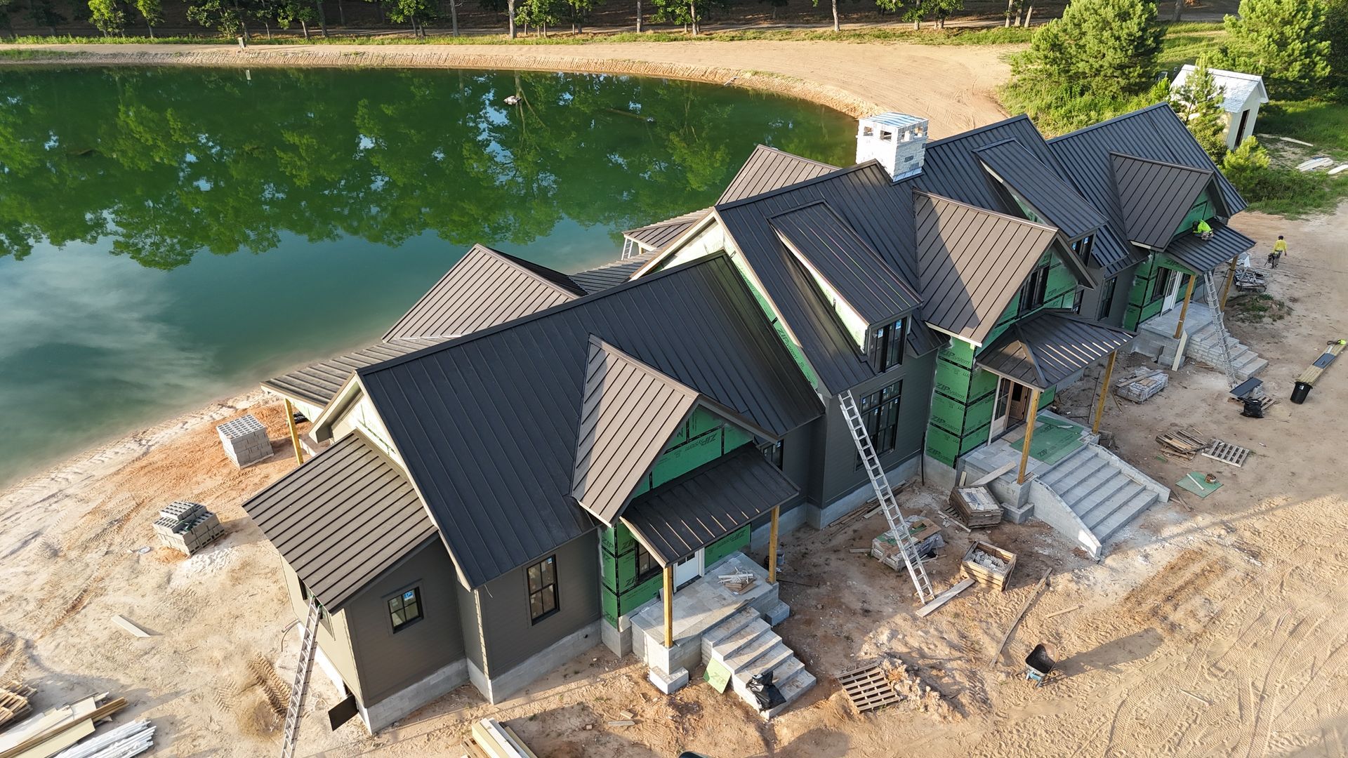 An aerial view of a house under construction next to a lake.