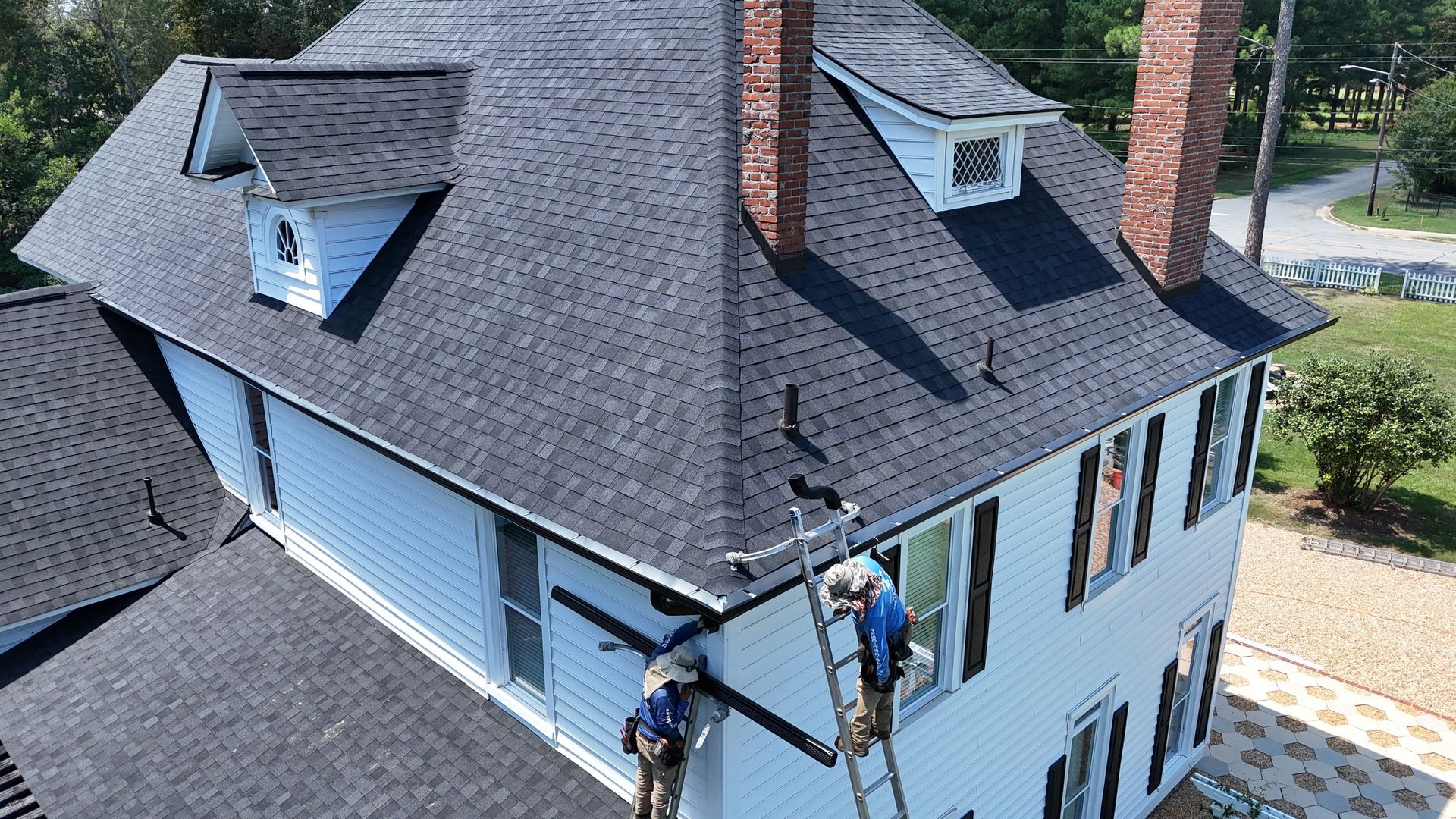 A group of people are working on the roof of a house.