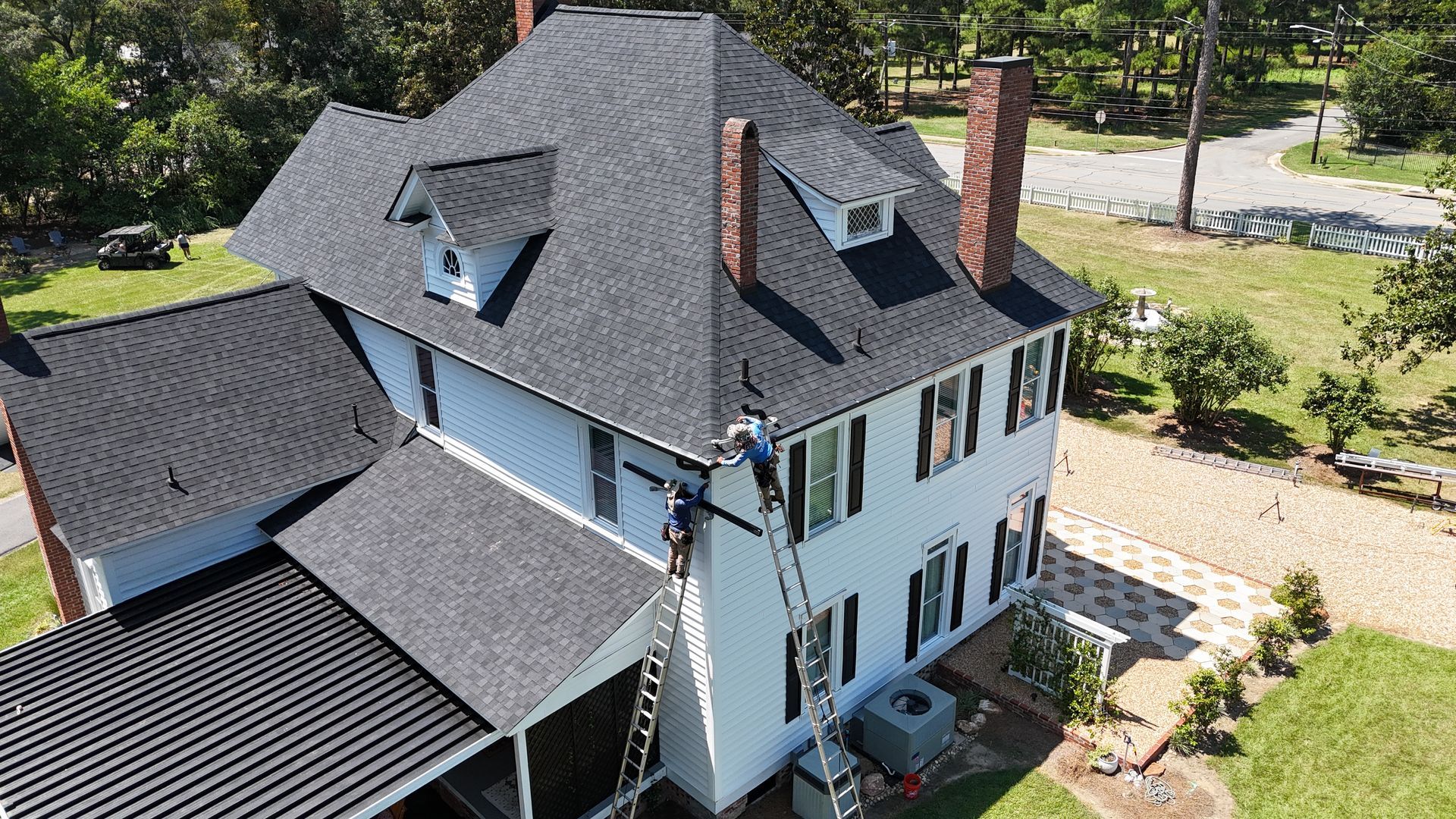 An aerial view of a large white house with a black roof.