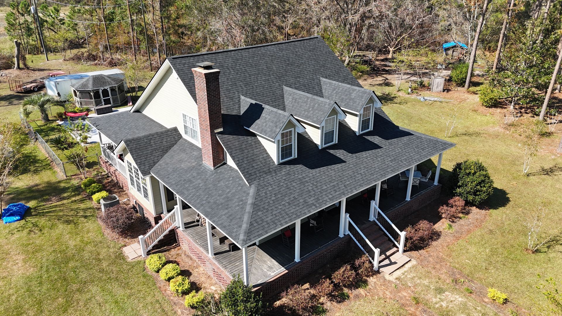 An aerial view of a large house with a porch and a roof.