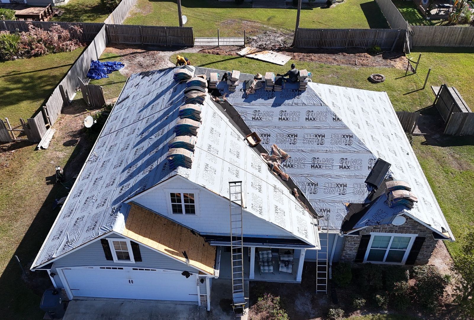 An aerial view of a house under construction with a roof being installed.