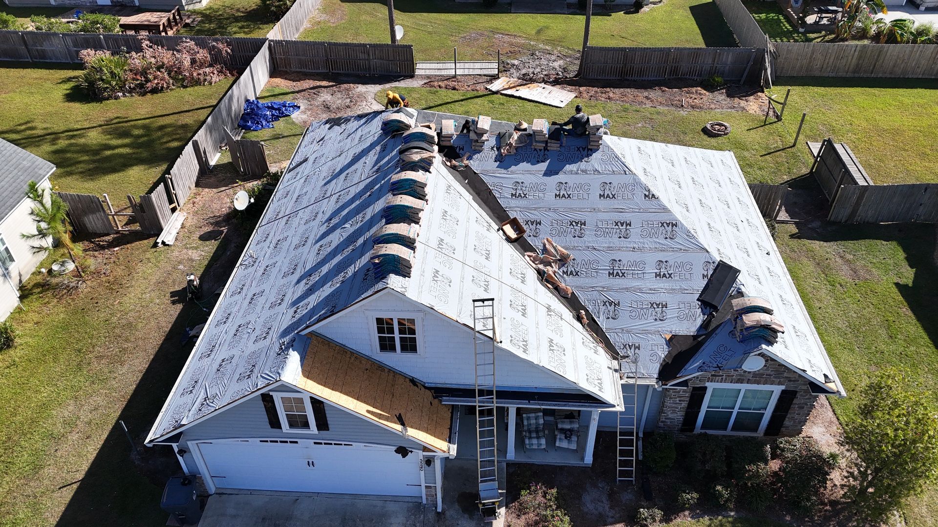 An aerial view of a house under construction with a roof being installed.