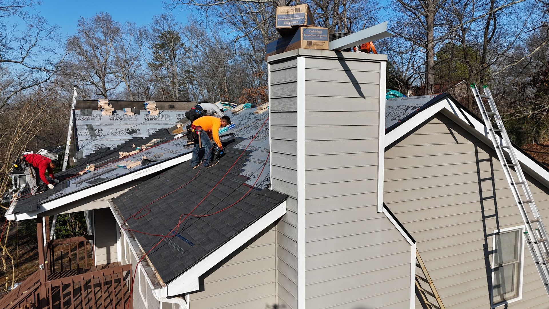 A group of men are working on the roof of a house.