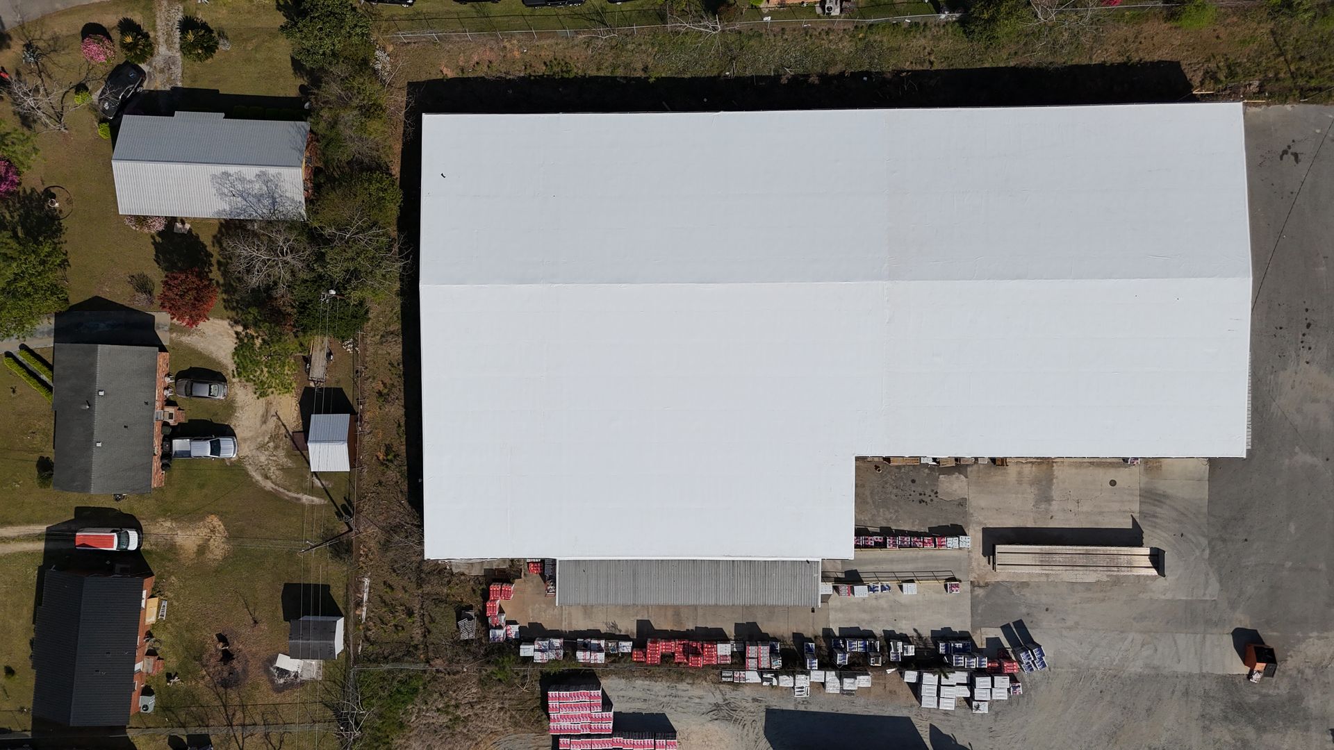An aerial view of a large building with a white roof surrounded by trees.