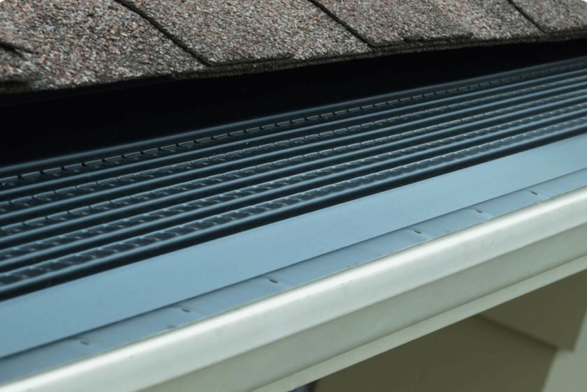 A close up of a gutter with a roof in the background