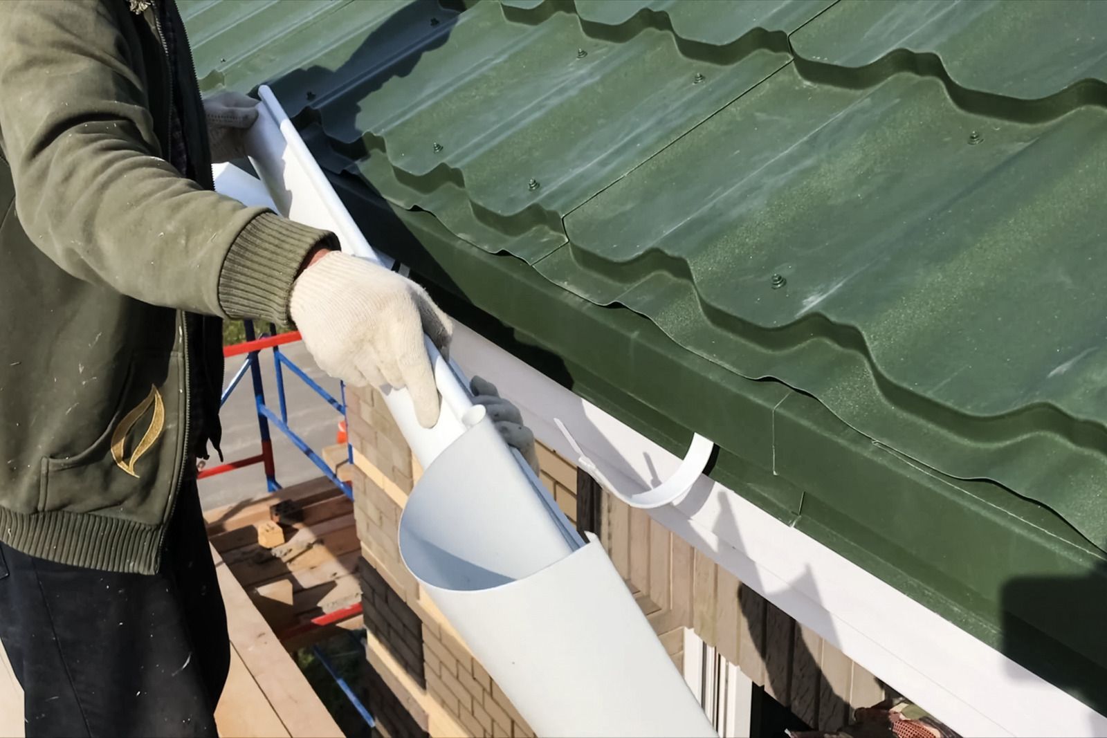 A man is installing a gutter on a green roof.