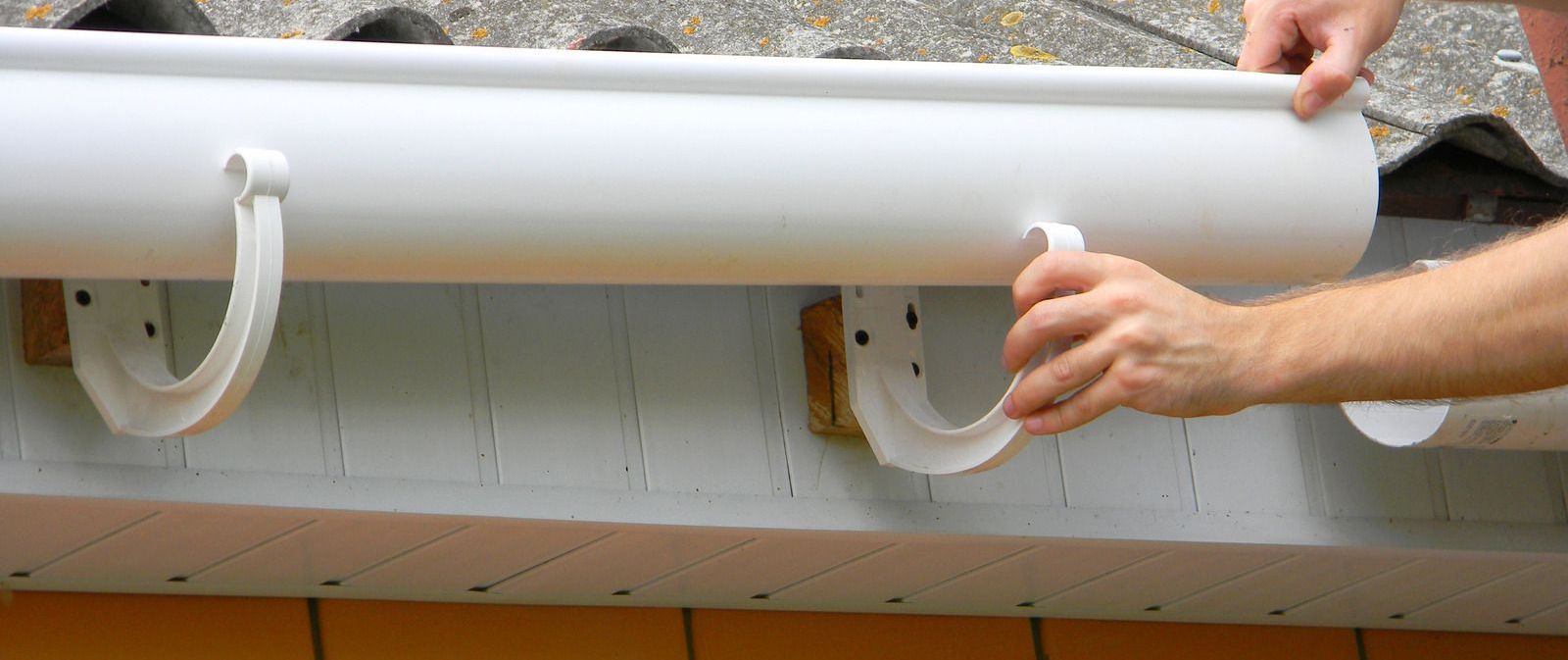 A person is installing a gutter on a roof.