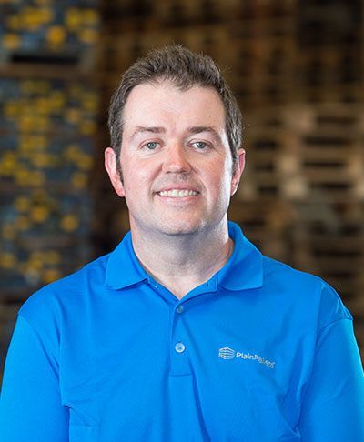 A man wearing a blue polo shirt is smiling for the camera.