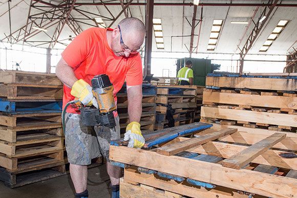 A man is working on a wooden pallet in a factory.