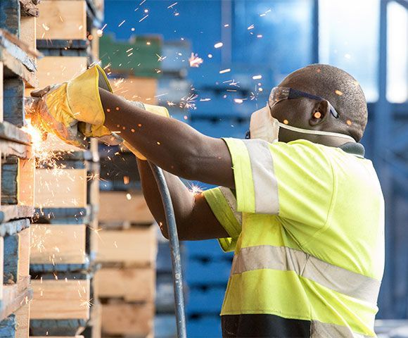 A man is cutting a piece of wood with a grinder in a factory.