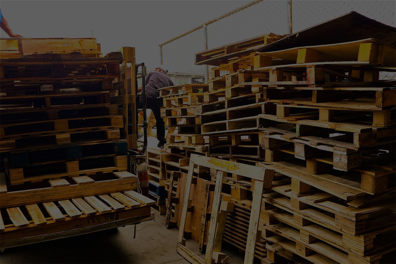 A pile of wooden pallets are stacked on top of each other in a warehouse.