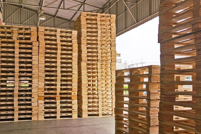 A warehouse filled with lots of wooden pallets stacked on top of each other.