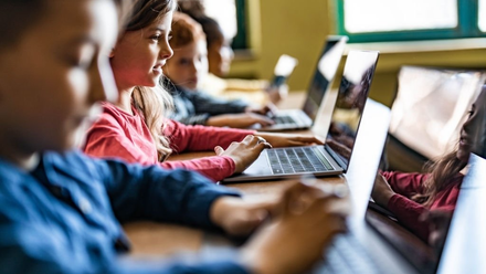 A group of children are using laptops in a classroom.