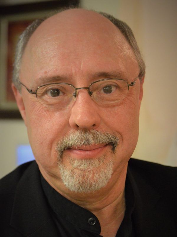 A man with glasses and a beard is smiling for the camera.