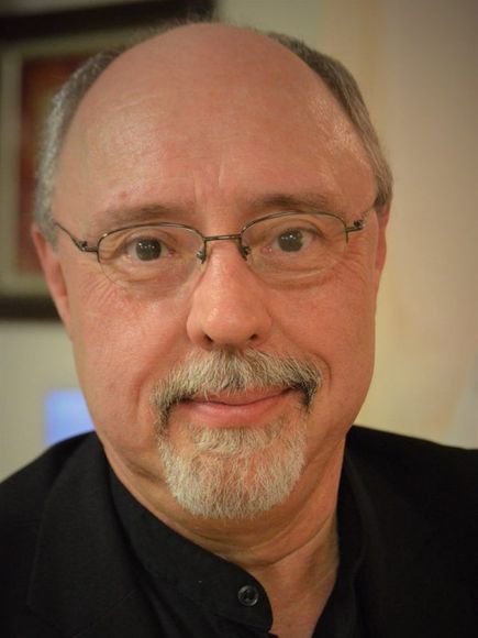 A man with glasses and a beard is smiling for the camera.
