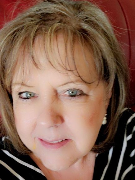 A close up of a woman 's face wearing a striped shirt and earrings.