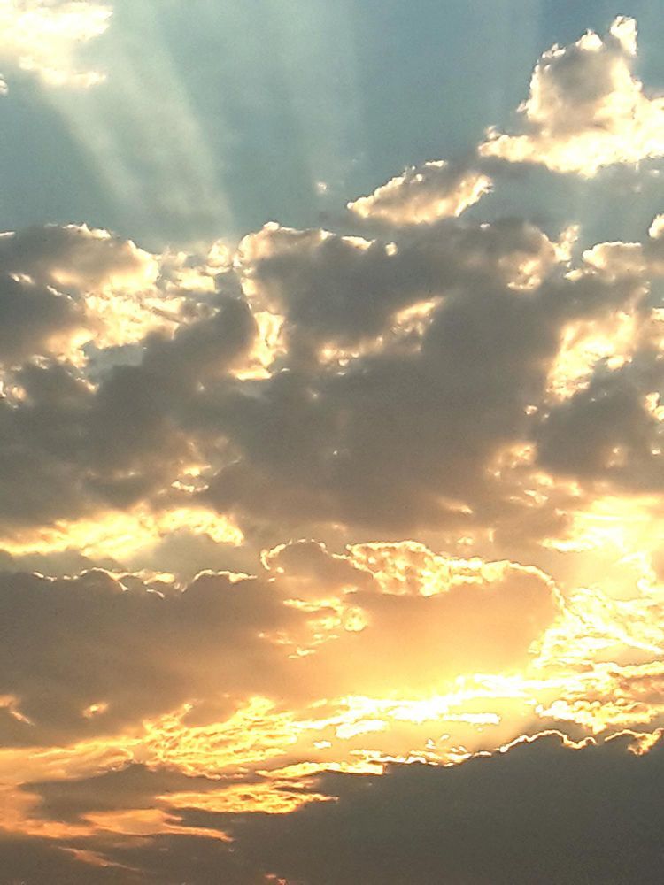 Sun breaking through clouds; golden light and blue sky.