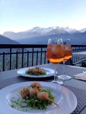 Due spritz Aperol e cibo fritto su piatti con vista sulle montagne innevate.