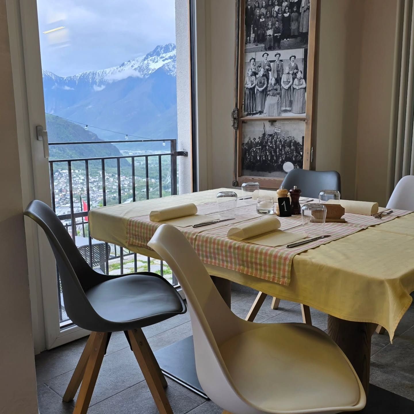 Tavolo da ristorante apparecchiato per cenare con vista sulle montagne e foto sulla parete.