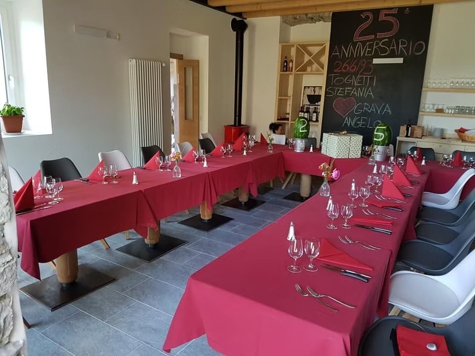 Apparecchiatura formale del tavolo da pranzo in un ristorante per festeggiare il 25° anniversario: tovaglia rossa, sedie bianche, cartello con lavagna.