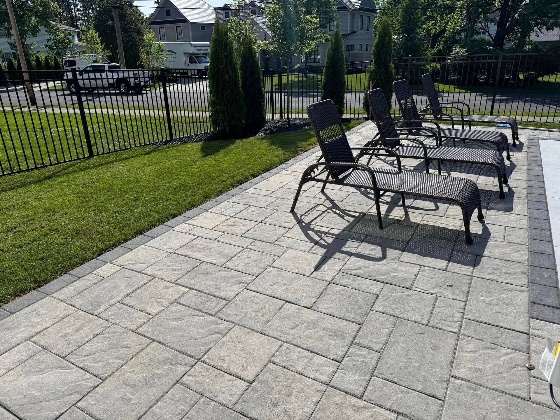 A patio with lawn chairs and a fence in the background.