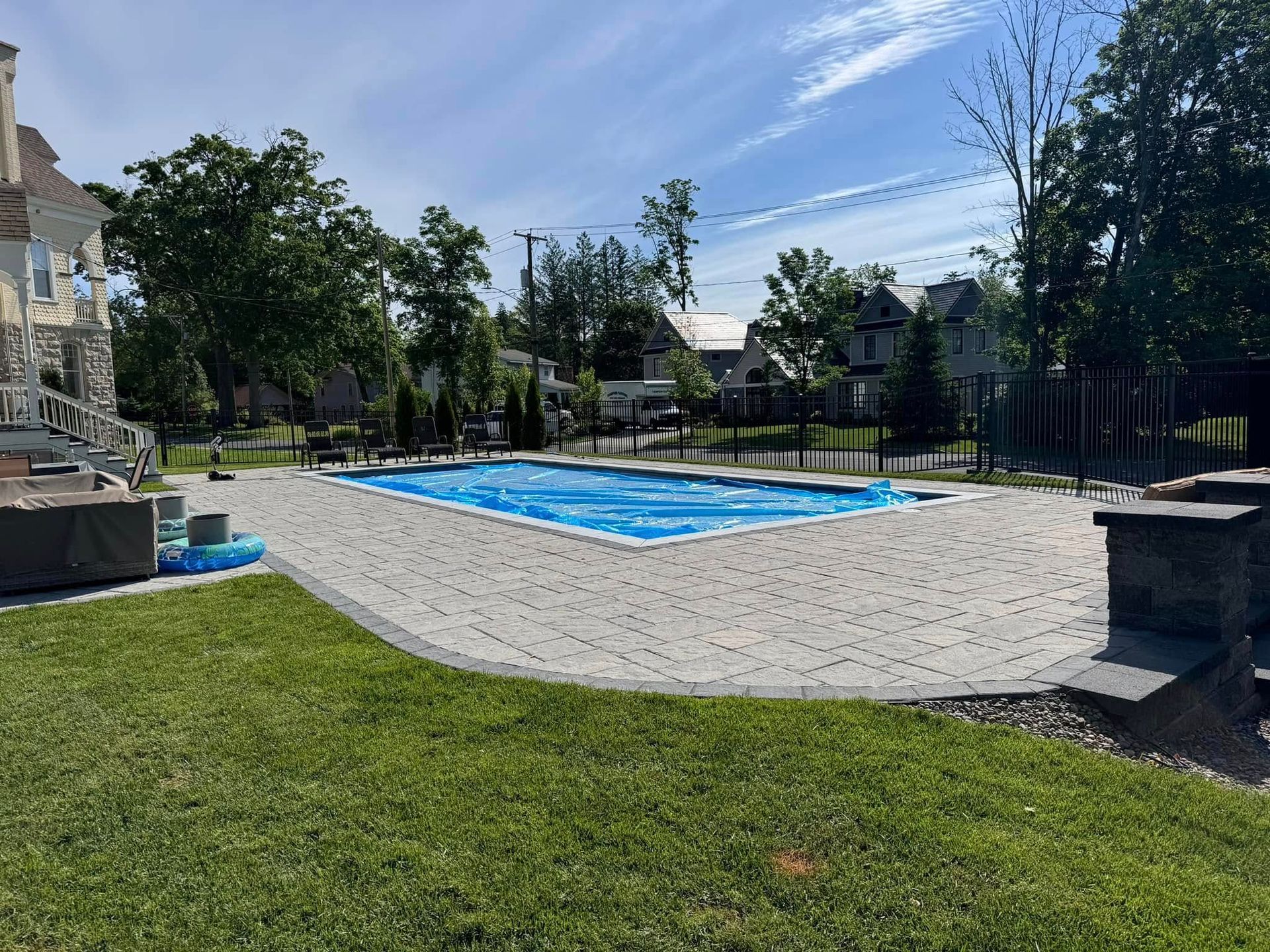 There is a large swimming pool in the backyard of a house.
