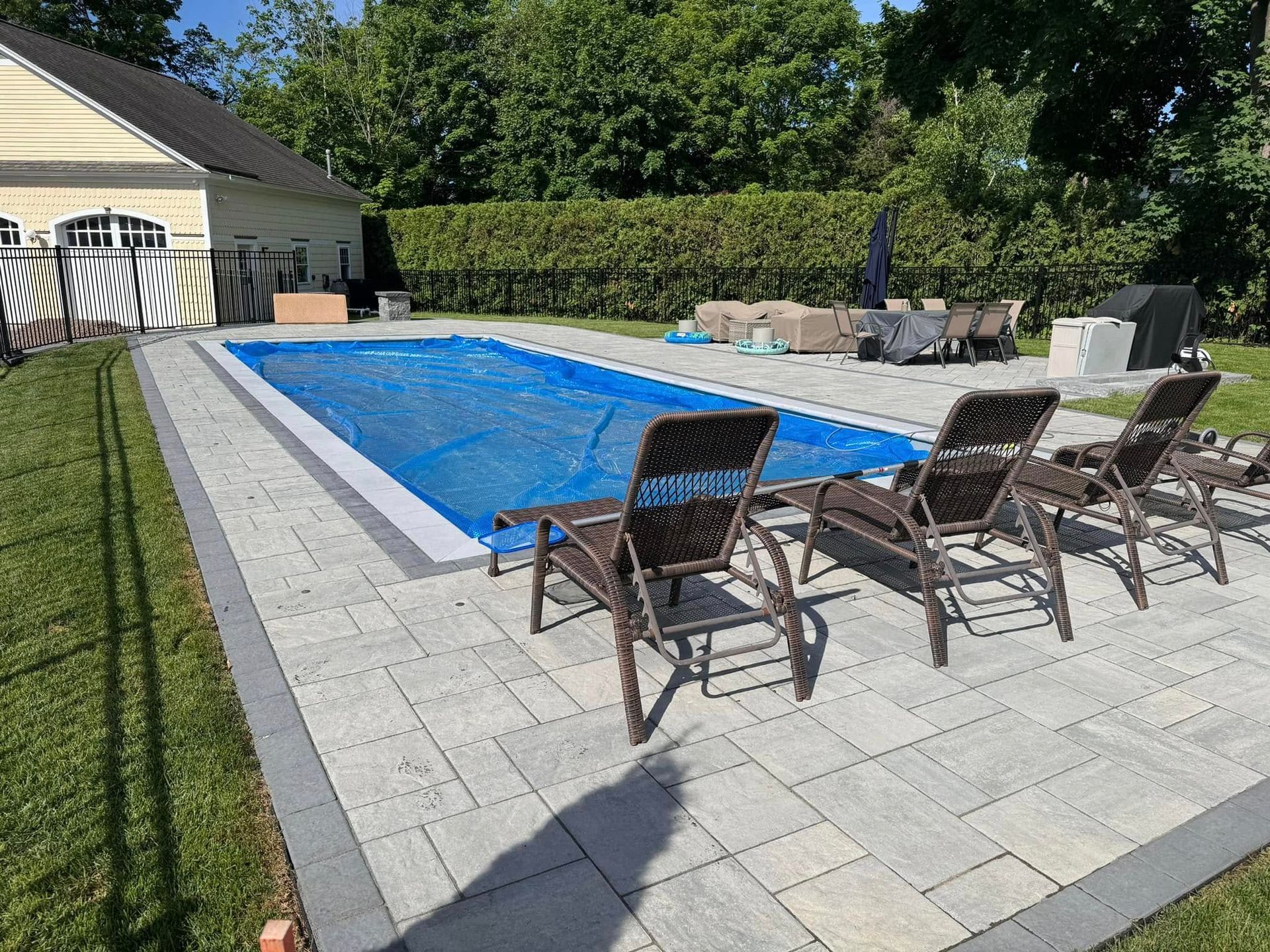 A large swimming pool is surrounded by chairs and a patio.