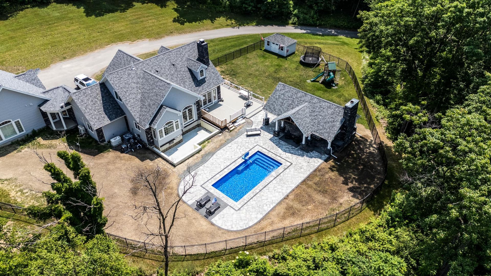 An aerial view of a house with a large swimming pool in the backyard.