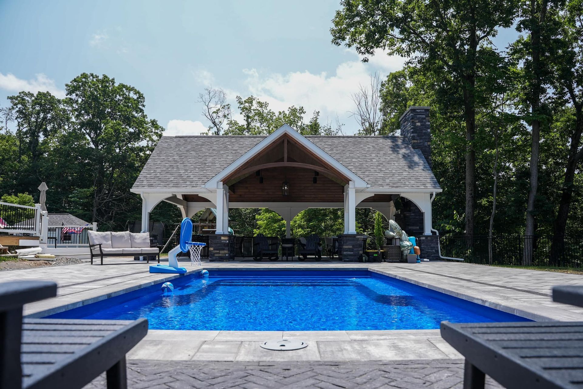 A large swimming pool with a gazebo in the background surrounded by trees.