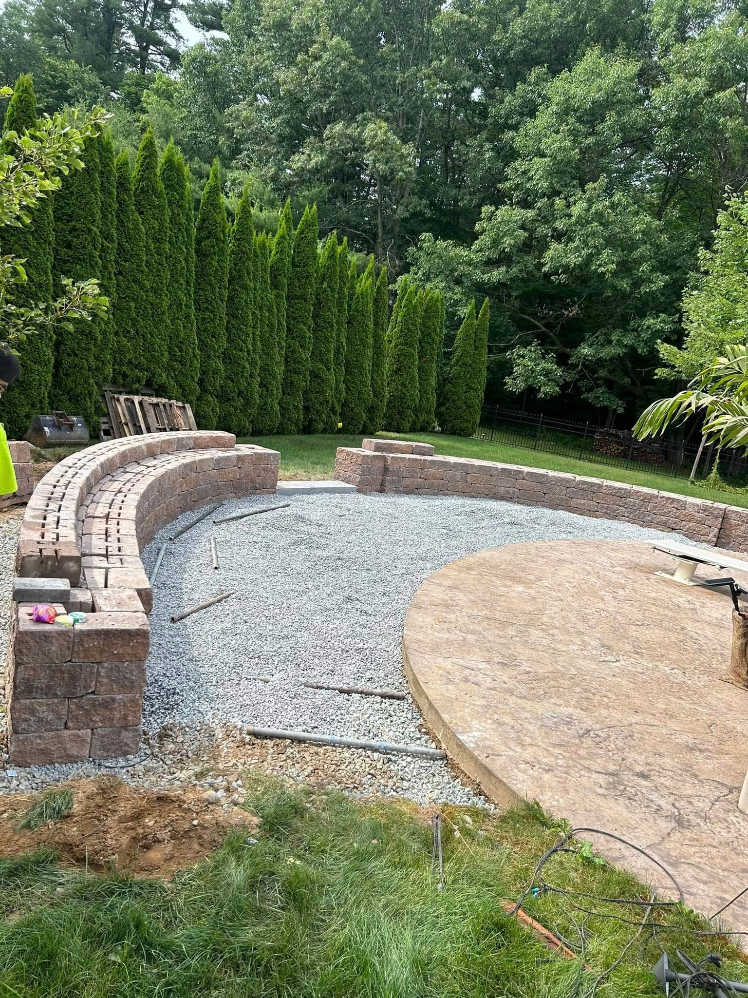A man is working on a patio in a backyard.