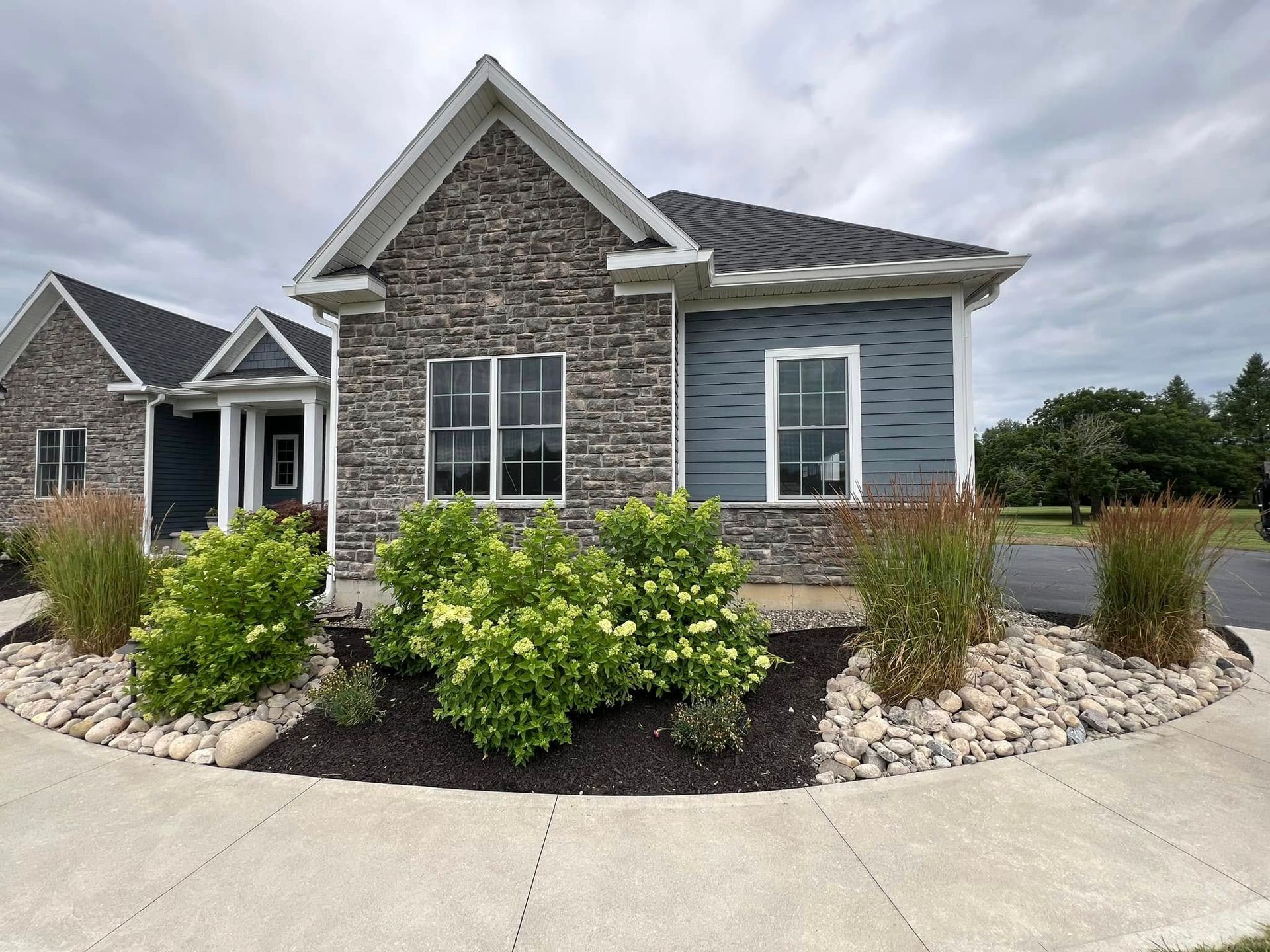 A small house with a stone facade and blue siding