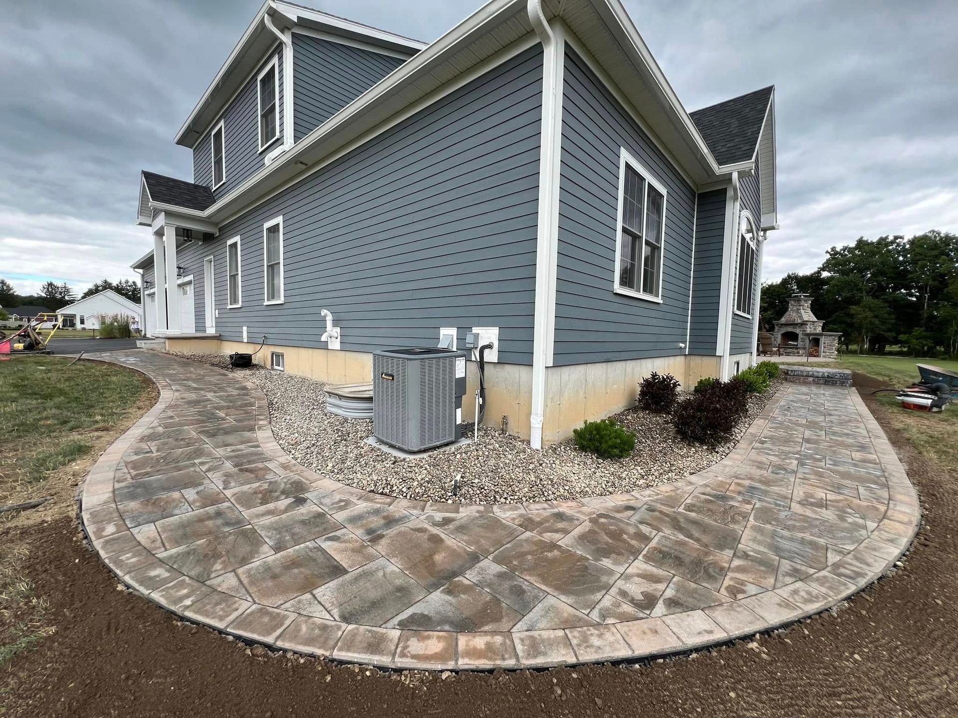 A large gray house with a stone walkway leading to it.