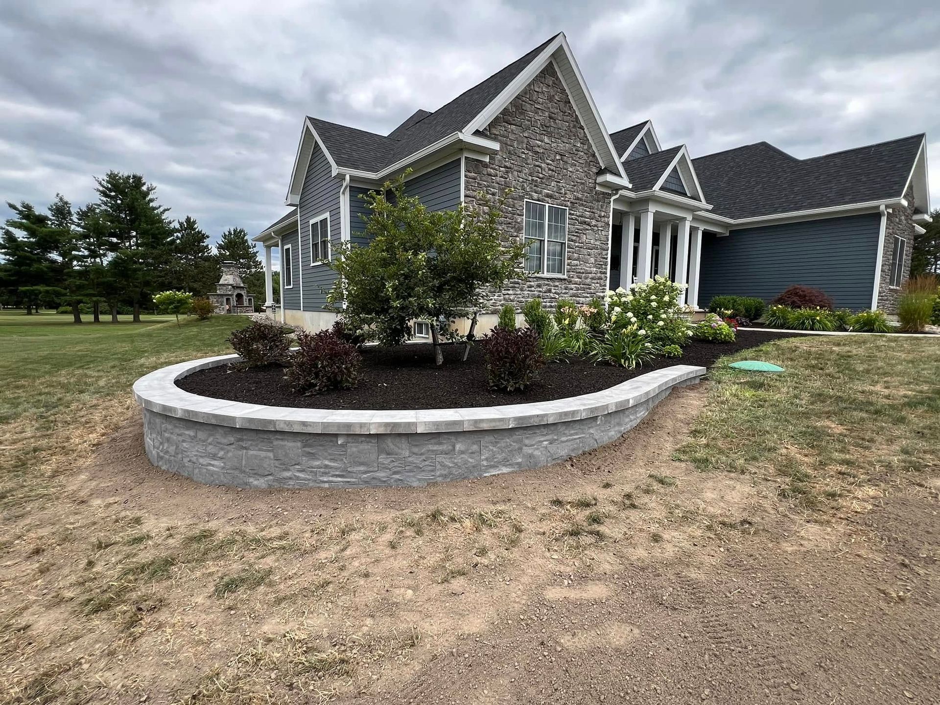 A large house with a circular planter in front of it.