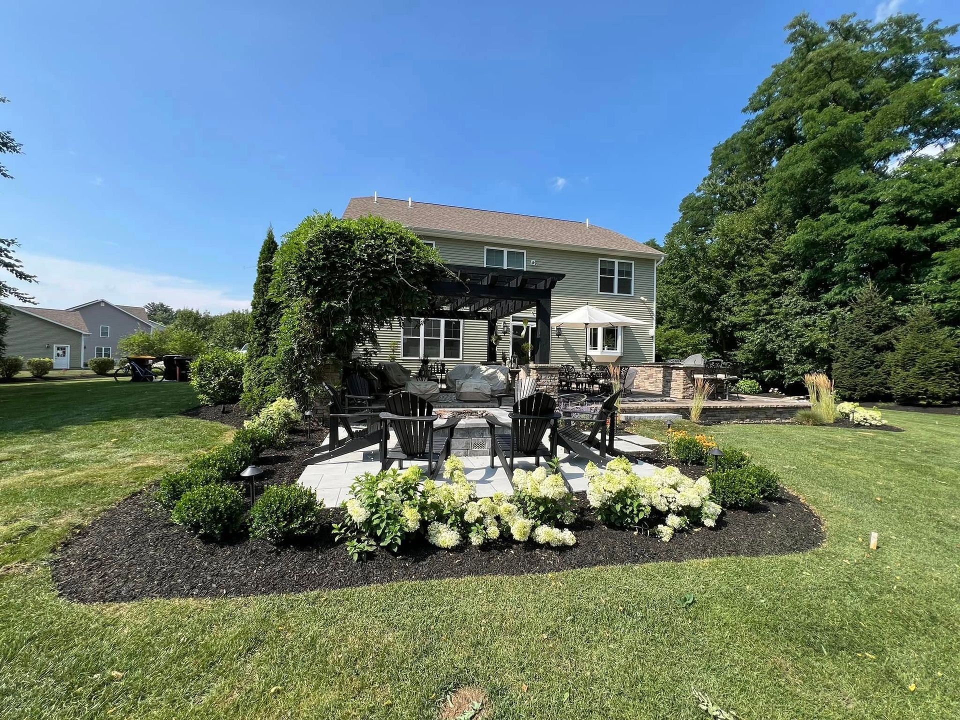 A large house with a patio and a pergola in the backyard.